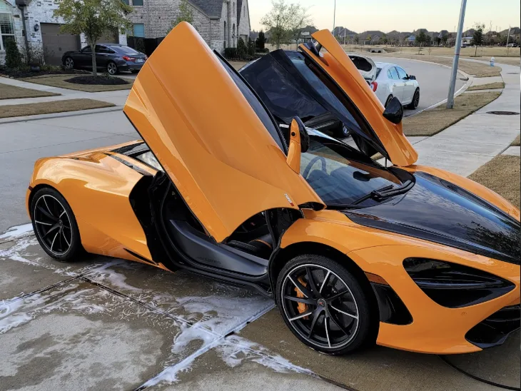 Orange McLaren 720S with its doors open after a wash