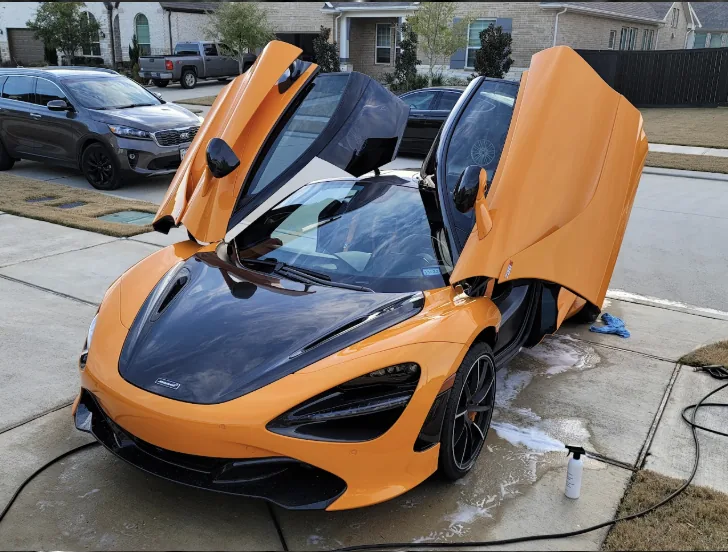 Orange McLaren 720S with its doors up during a driveway detail