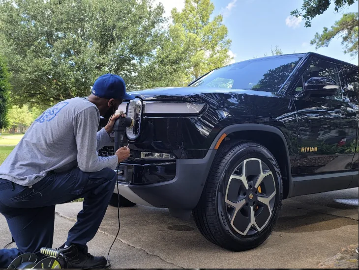 Machine polishing the front end of a black Rivian R1T