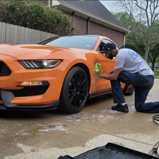 Wiping down an orange Shelby GT350 during a driveway detail